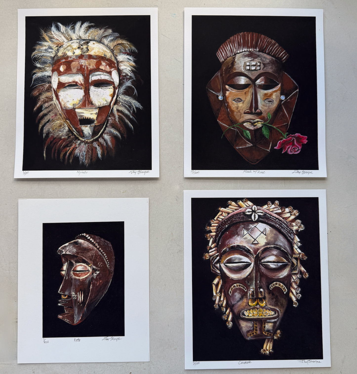 Four framed artworks of stylized masks on a wall.