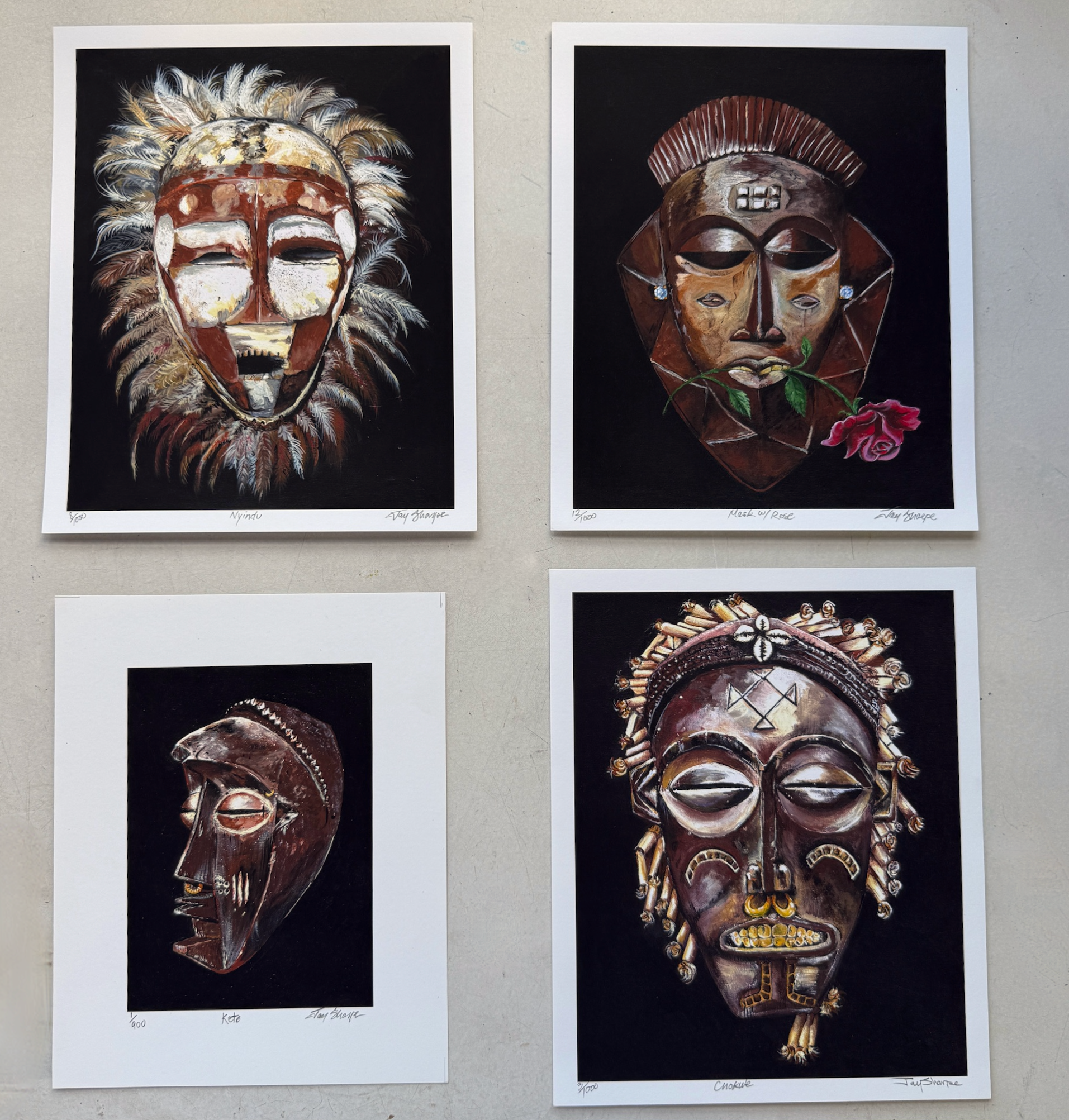 Four framed artworks of stylized masks on a wall.